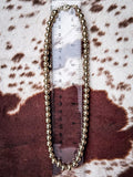 Beaded gold toned necklace displayed on a ruler