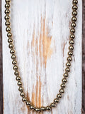 Gold toned beaded necklace on a wooden background