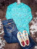 Turquoise Western paisley long sleeve base layer laid flat on cowhide background