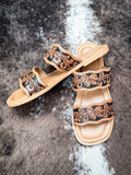 Pair of Myra sandals with western-style floral tooling and two straps on neutral background.