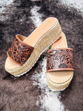 Top-down view of MYRA brand sandals with floral carved leather straps and beige footbeds.