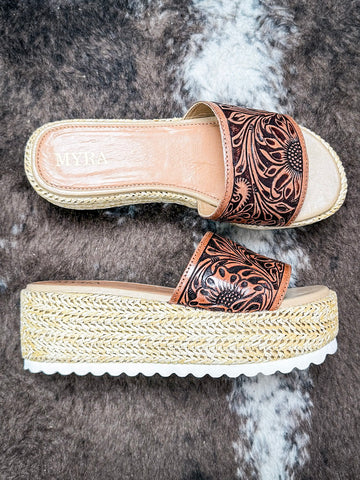 Side view of platform sandals featuring floral tooled leather upper and woven jute wedge sole.