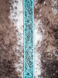 Detailed view of floral tooling on turquoise western belt with black accents.