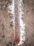 Detailed floral tooling on brown leather western belt with natural stitching.