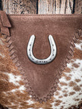 Close-up of MYRA suede bag featuring silver horseshoe embellishment and cowhide texture