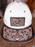 Close-up of western trucker hat featuring detailed tooled leather patch and brim