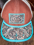 Close-up of turquoise tooled leather patch and brim on brown western trucker hat