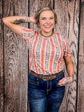 Woman wearing patterned puff sleeve top tucked into high-waisted jeans with a tooled leather belt.