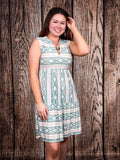 Smiling woman modeling Lucky & Blessed Desert Skies Sleeveless Dress against rustic wood backdrop.