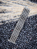 Angled silver Apple Watch band with multiple metal studs on organic black bean surface