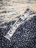 Rustic silver heart Apple Watch band on black beans and wheat grass backdrop