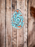 Tooled leather teardrop earring with turquoise floral scrollwork measured against clear ruler