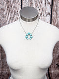 Turquoise colored squash blossom necklace displayed on mannequin bust with rustic wood background.
