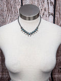 Southwestern silver squash blossom necklace with turquoise stones displayed on mannequin bust.