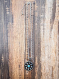 Western concho necklace with turquoise and silver detailing laid flat on wood surface with ruler