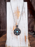 Vintage western round pendant necklace with turquoise center and silver beads on rustic wood stand