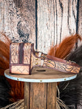 side of fanny pack on wood table, feathers and wheat in background, wood backdrop