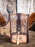 side of fanny pack on wood table, feathers in background, wood backdrop
