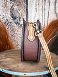 shoulder bag on wood table, feathers in background, wood backdrop