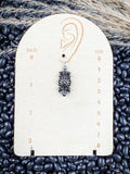 Earrings displayed on measurement board.