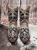 Front view of boots displayed on cowhide and wood backdrop.