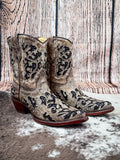Side view of boots displayed on cowhide and wood backdrop.