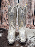 Front view of boots on cowhide and wood backdrop.