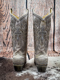 Back view of boots on cowhide and wood backdrop.