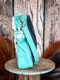 Side view of the Delight Hand Tooled Bag on a wood table, wood back drop.