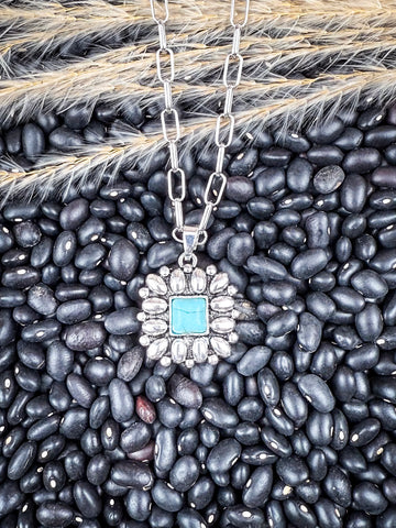 The Aster Pendant Necklace displayed on beans and wheat.