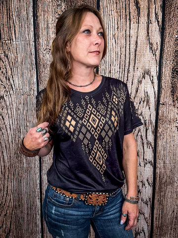 Model posing wearing the Black Canyon Top in front of a wood background.
