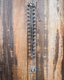 Three Trails Squash Blossom Fashion Necklace shown with a ruler, wood back drop.
