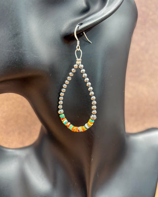 A single dangling beaded earring displayed on a black mannequin head. The earring has a silver-toned fishhook and wire connector, a teardrop-shaped row of small metallic beads, and a curved bottom section with small multicolored beads including orange, green, yellow, and white.
