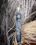Cheyenne Bloom Hand-Tooled Key Fob displayed on wheat, wood back drop.