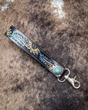 Cheyenne Bloom Hand-Tooled Key Fob displayed on cow hide.