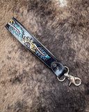 Cheyenne Bloom Hand-Tooled Key Fob displayed on cow hide.