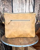 Back view of the Fennington Leather Bag in Carmel on a wood table with a wood back drop.