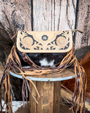Front view of the Coral Paz Hand-Tooled Bag on a wood table with a wood back drop.