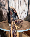 Side view of the Coral Paz Hand-Tooled Bag on a wood table with a wood back drop.