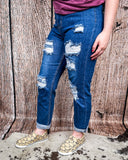 Side view of a girl modeling the Downtown Distressed High-Rise Mom Jeans standing on cowhide.