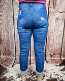 Back view of a girl modeling the Downtown Distressed High-Rise Mom Jeans standing on cowhide.
