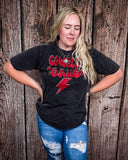 A girl modeling the Cowgirl Gang Vintage Graphic Tee with a wood back drop.