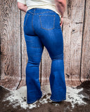 Back view of a girl modeling the Saloon Stretch Five Button Flare Jeans while on cowhide.