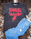 The Cowgirl Gang Vintage Graphic Tee displayed on cowhide along with jeans.