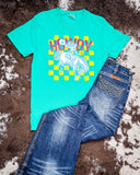 Front view of the Buckin Babe Howdy Graphic Tee displayed on cowhide along with jeans.