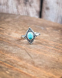 The Bahman Adjustable Genuine Turquoise Ring sitting on a table.