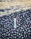 The Arrowhead Genuine Turquoise Necklace displayed on beans and wheat.
