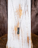 The Arrowhead Genuine Turquoise Necklace displayed on a wood plank.