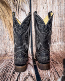 Back view of the Midnight Slither Corral Boots in a wood backdrop.