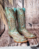 Side view of the High Noon Belle Corral Boots in a wood backdrop.